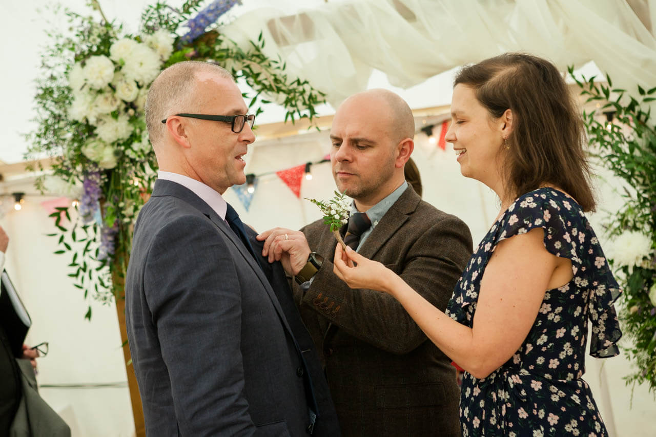 groom's sister fastens flowers to jacket