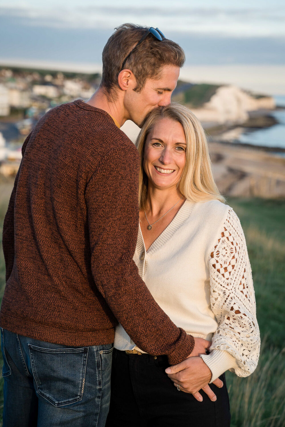 man kisses top of girlfriends head with arm around waist