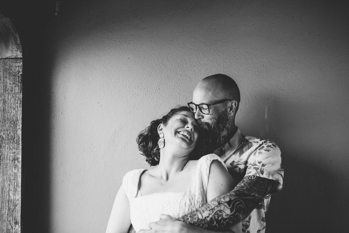 bride leaning back towards groom standing in nicely lit alcove