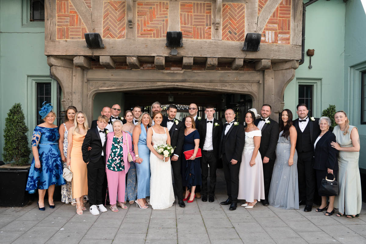 group shot of wedding party standing outside hotel du vin looking towards camera
