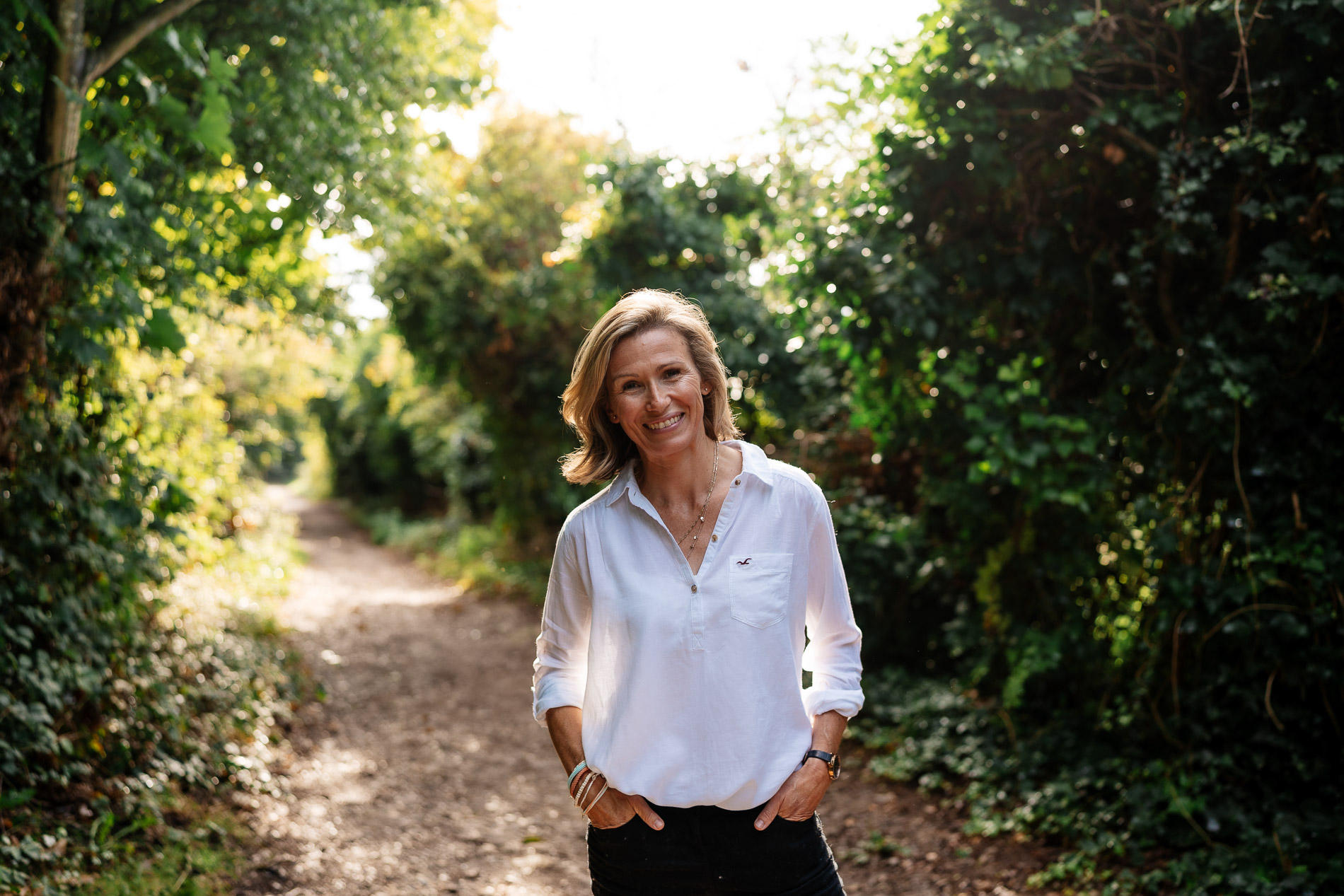 woman standing in country lane smiling and looking into the camera