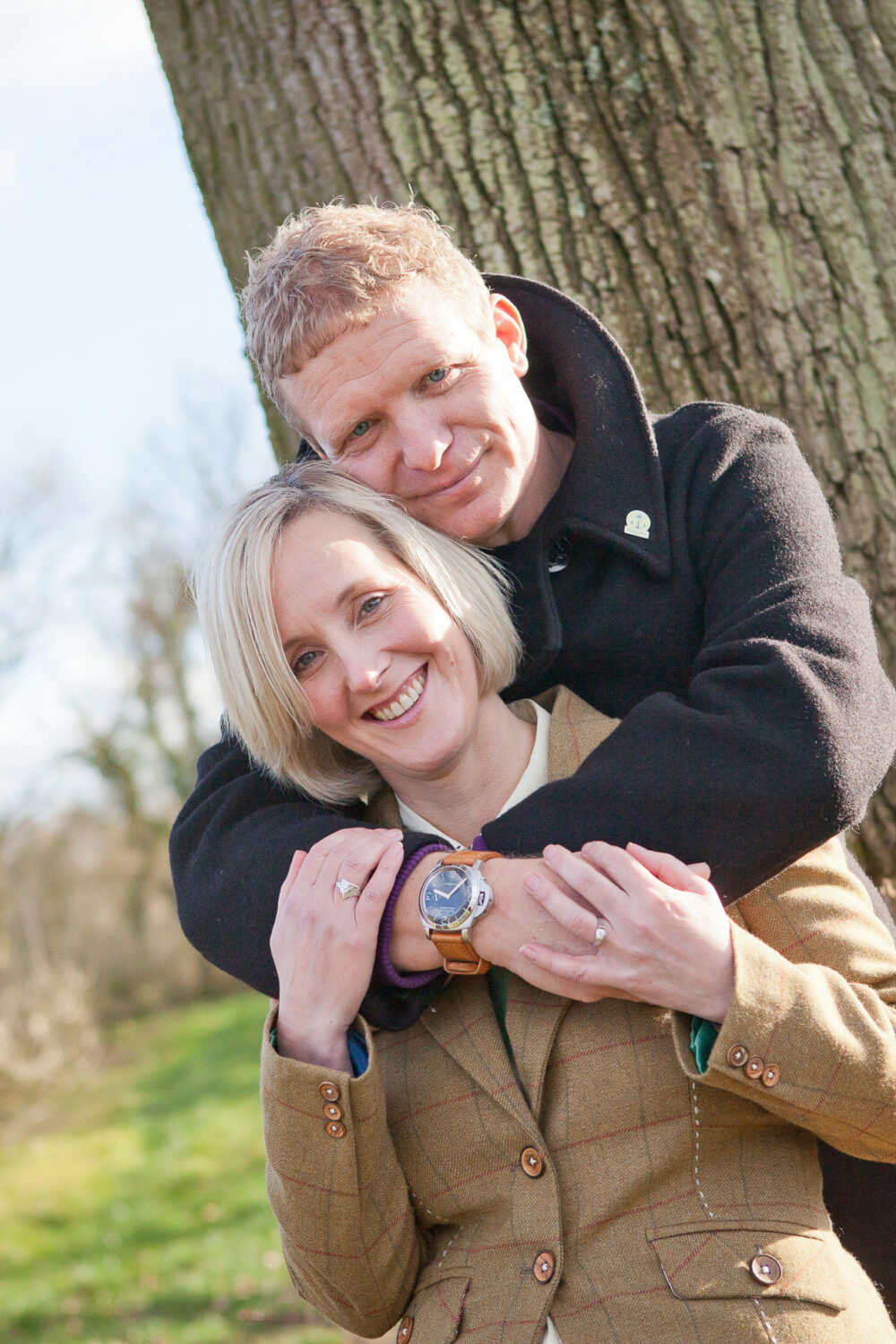 man puts arms around woman standing behind her both smiling at camera