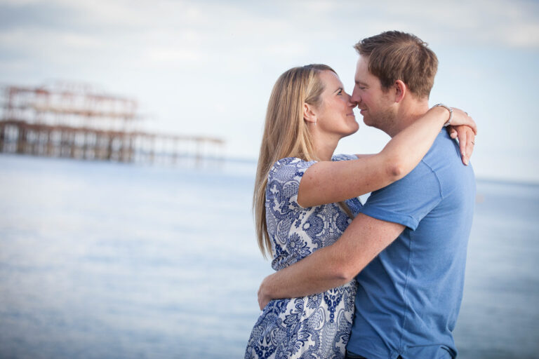 man and woman arm in arm kissing with sea in background