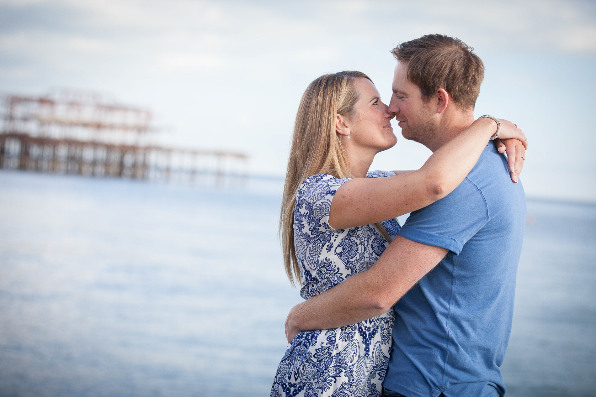 man and woman arm in arm kissing with sea in background