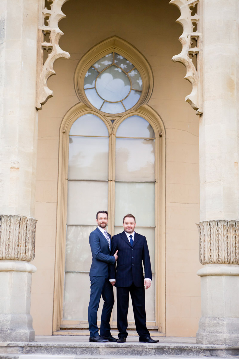dashing grooms stand together looking towards the camera under the pillars of the royal pavilion