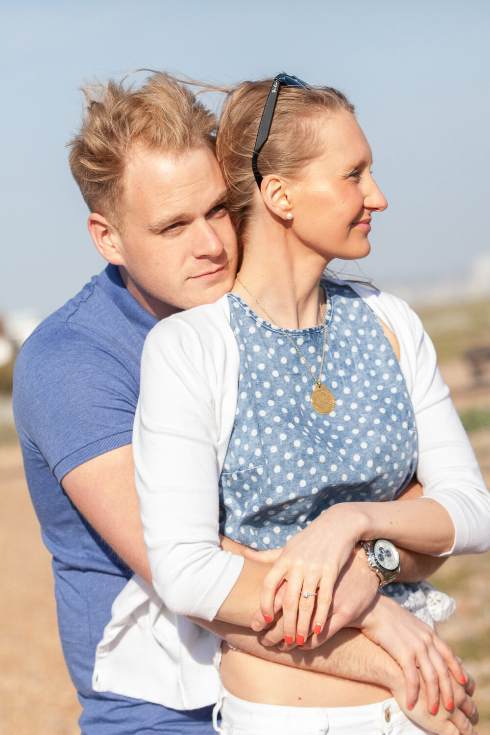 man wraps arms around fiancee leaning chin on her shoulder