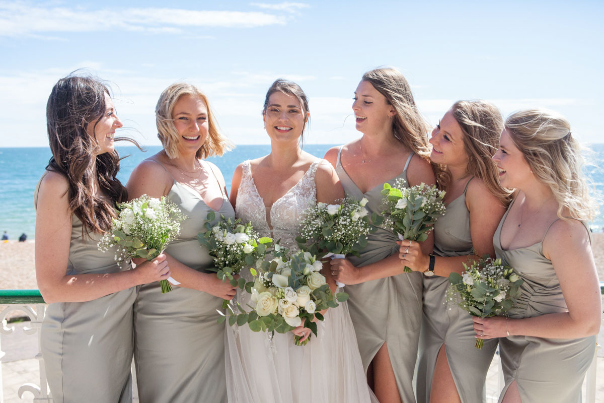 brides looks to camera for photos with her bridesmaids all looking towards her