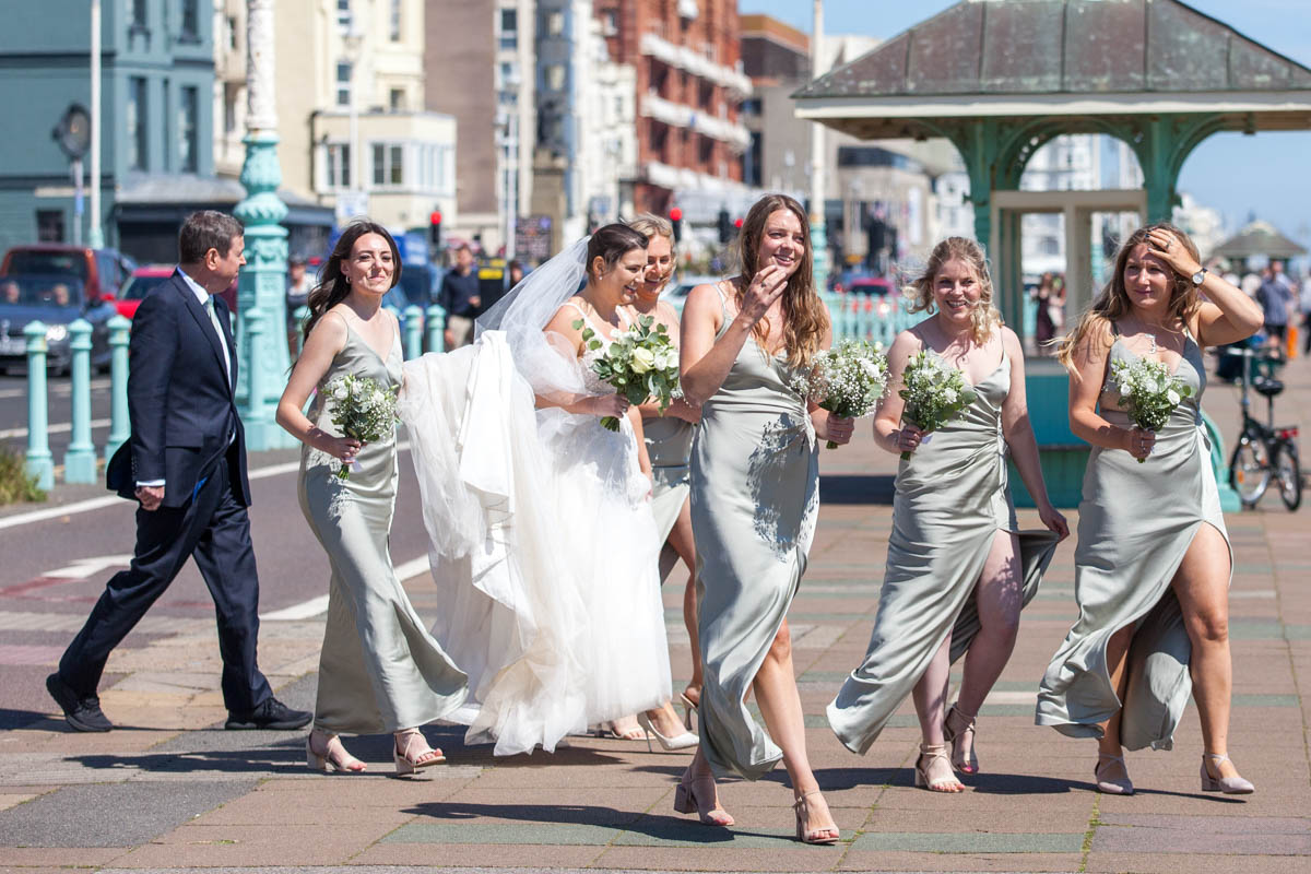 wedding party walking along seafront to bandstand