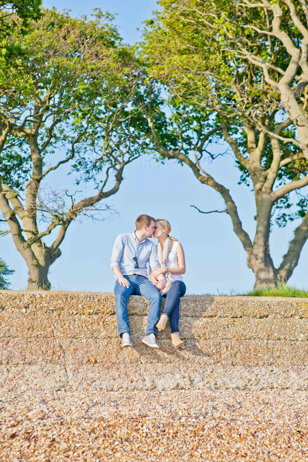 man and woman sitting on brick wall looking into each others eyes