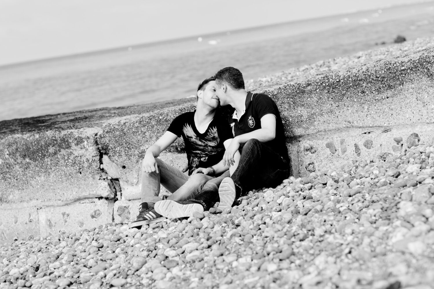 two guys sitting on Brighton beach kissing