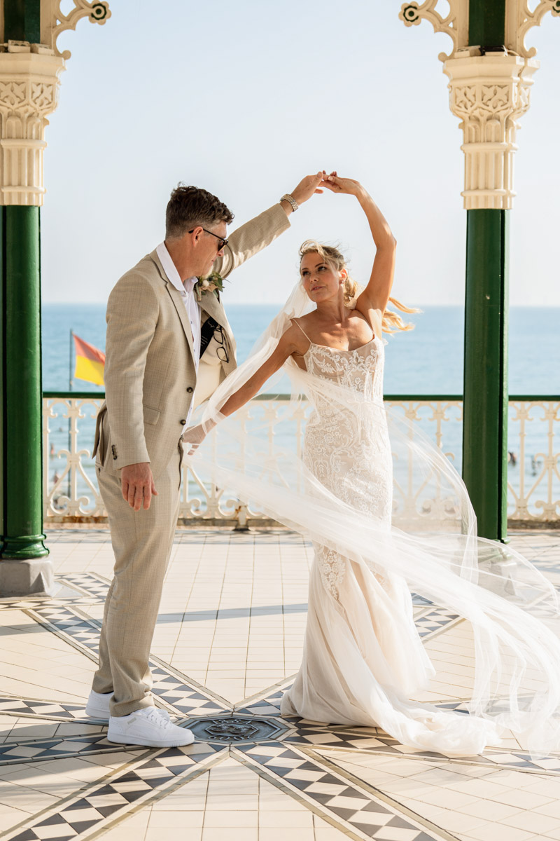 groom gives bride a twirl on Brighton bandstand