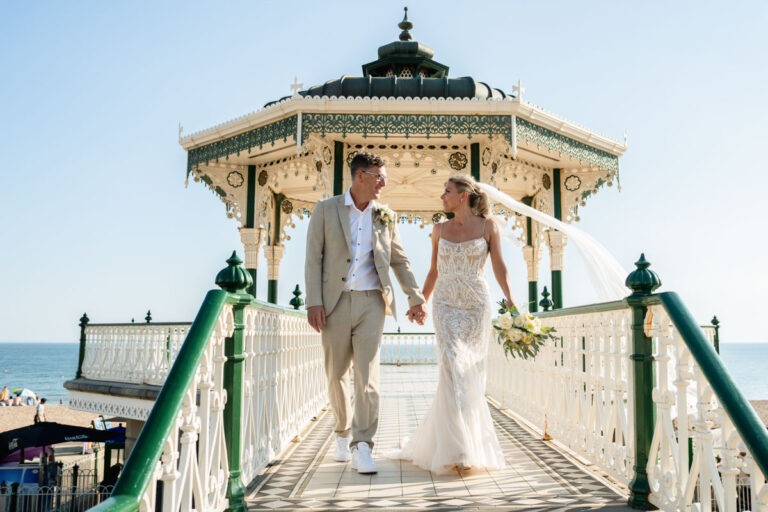 bride and groom walking off Brighton bandstand looking at each other