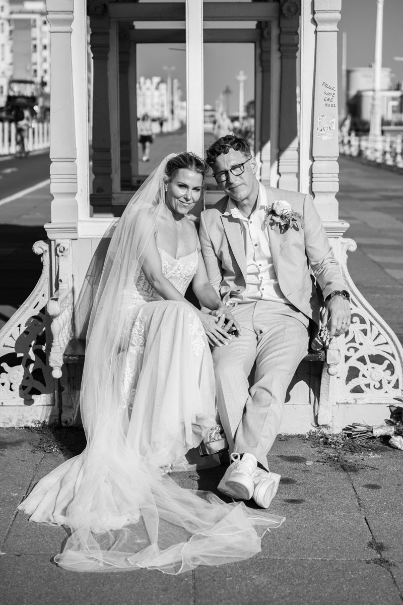 bride and groom sitting at bus stop on Brighton's main promenade