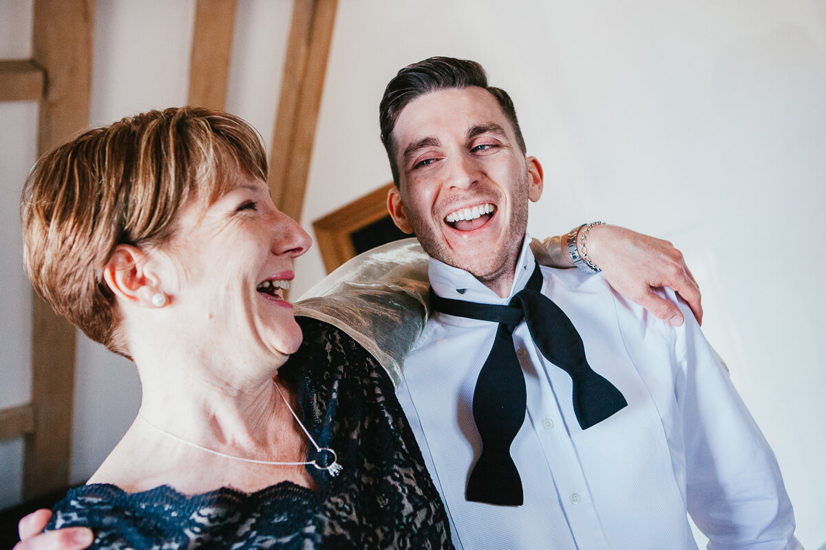groom laughing with his mother in law who has her arm around him