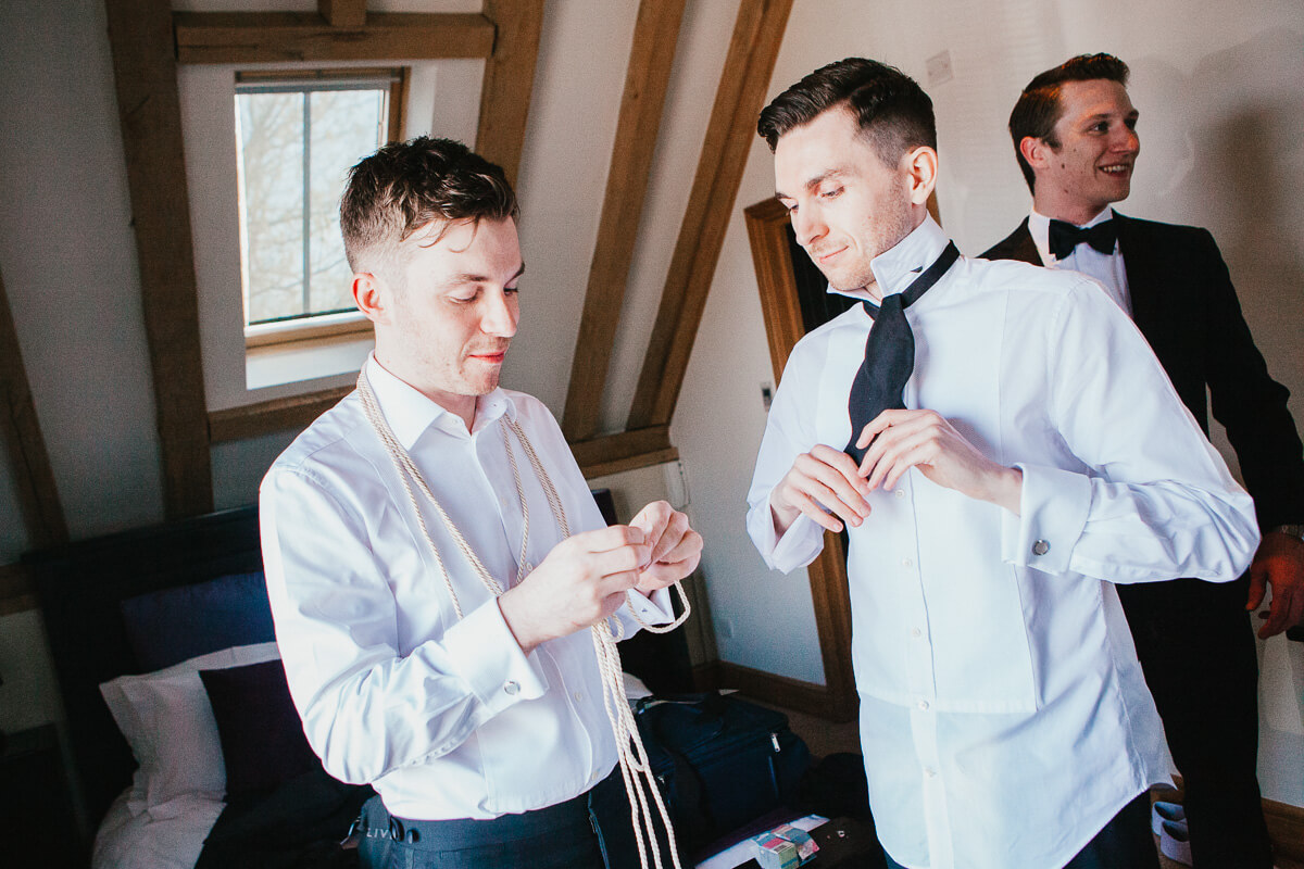 two grooms doing up their ties
