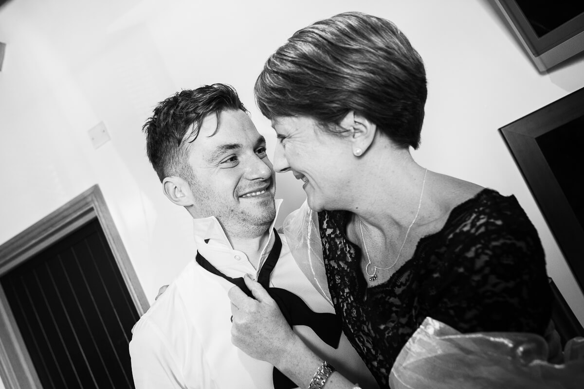 groom sharing an intimate moment with his mother smiling at each other