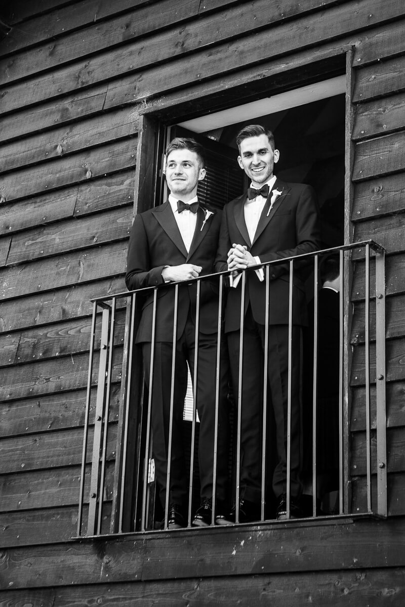 grooms standing in their tuxedoes on balcony