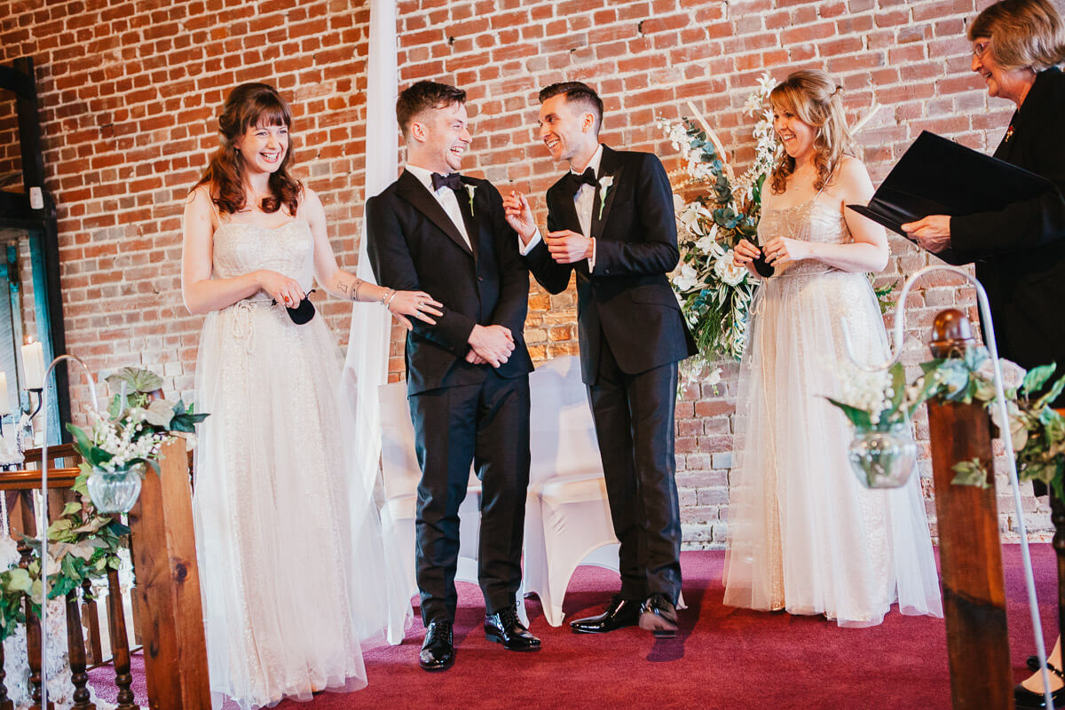 grooms standing in ceremony looking at each other with best women either side