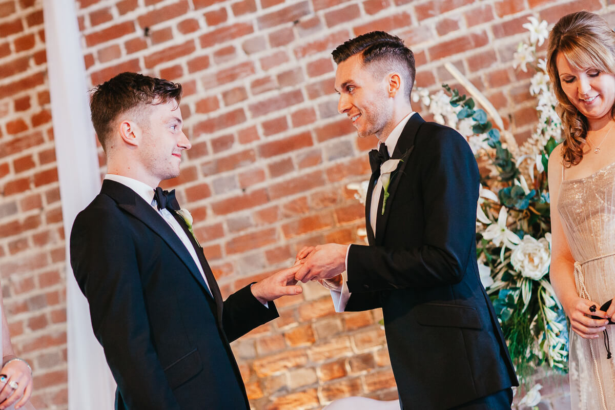 groom putting ring on other groom finger