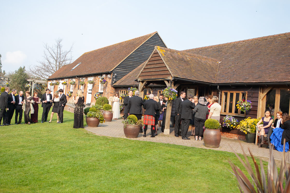 distant shot of cooling castle barn venue with guests mingling in background