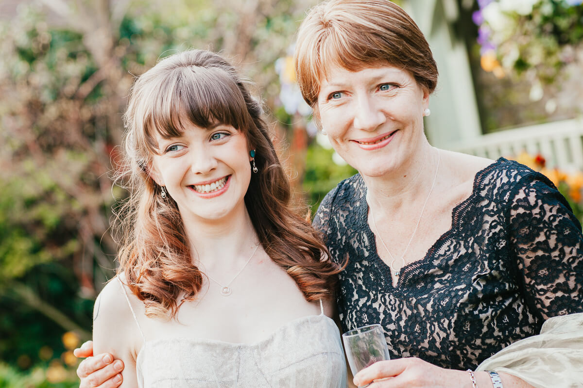 mother and daughter with arms round each other smiling at another guest