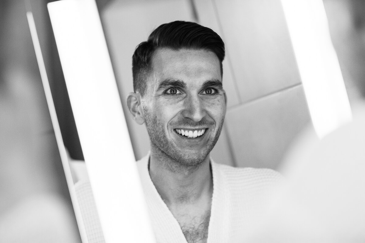 groom looking at himself in mirror while getting ready