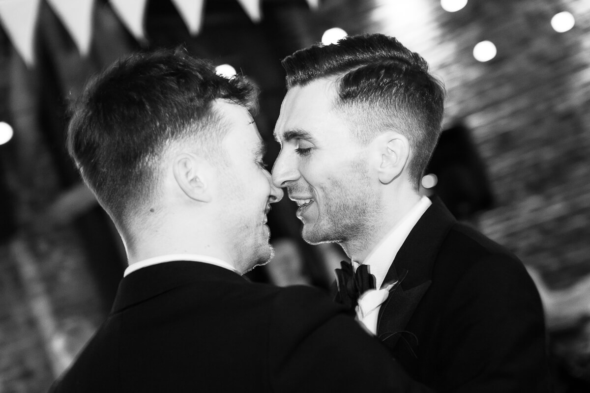first dance with two grooms faces close together