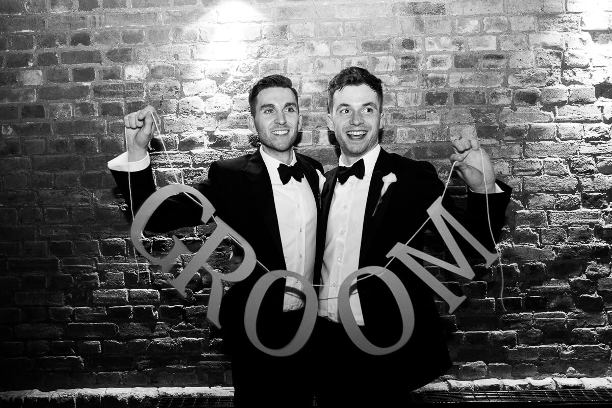 two grooms holding the giant wording groom