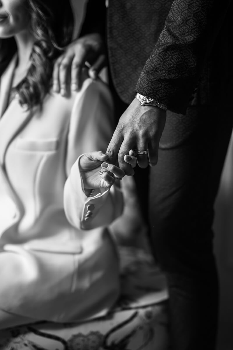 image of couple from chest down with groom and bride's fingers linked