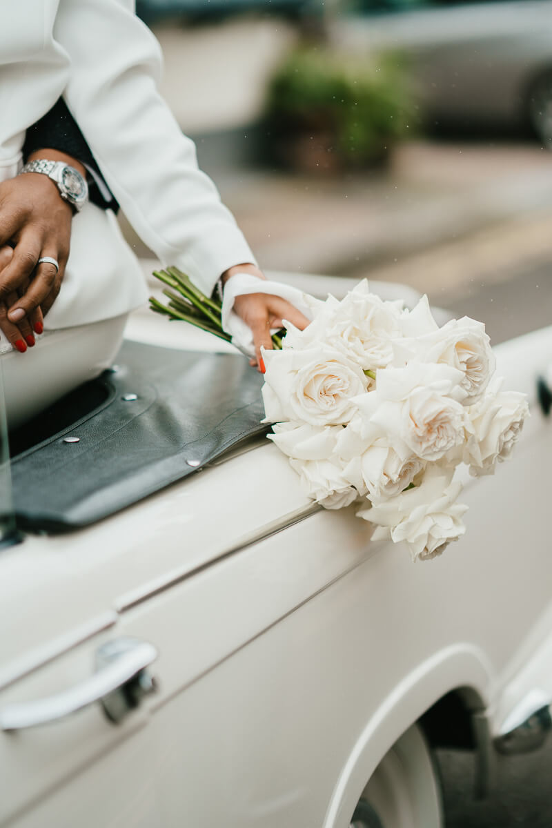 close up of white roses held over the side of classic car