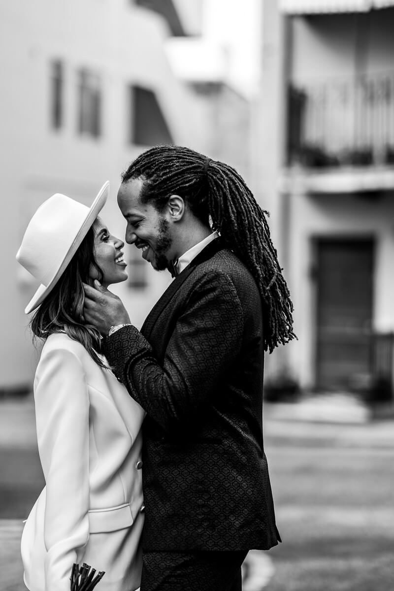 city in the background and couple portrait sideways on looking at each other with groom touching bride's face