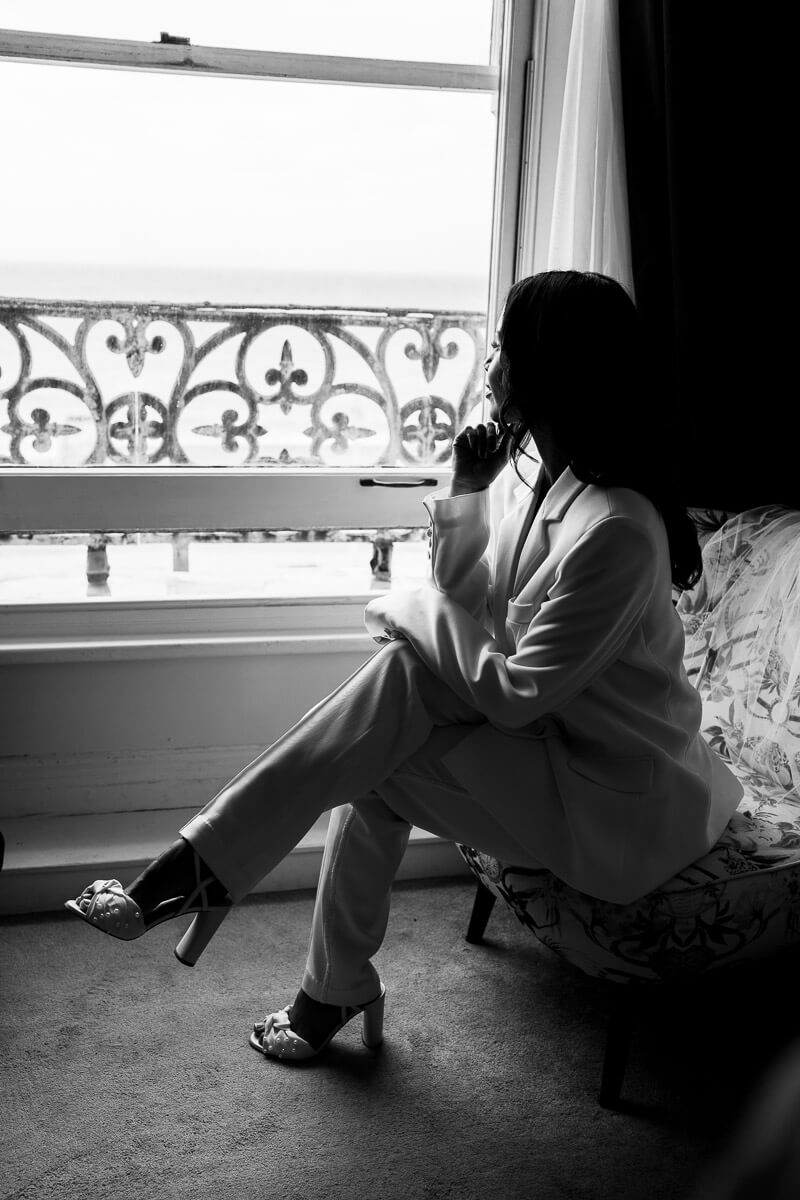silhouette of bride sitting on chair by window looking out to the sea