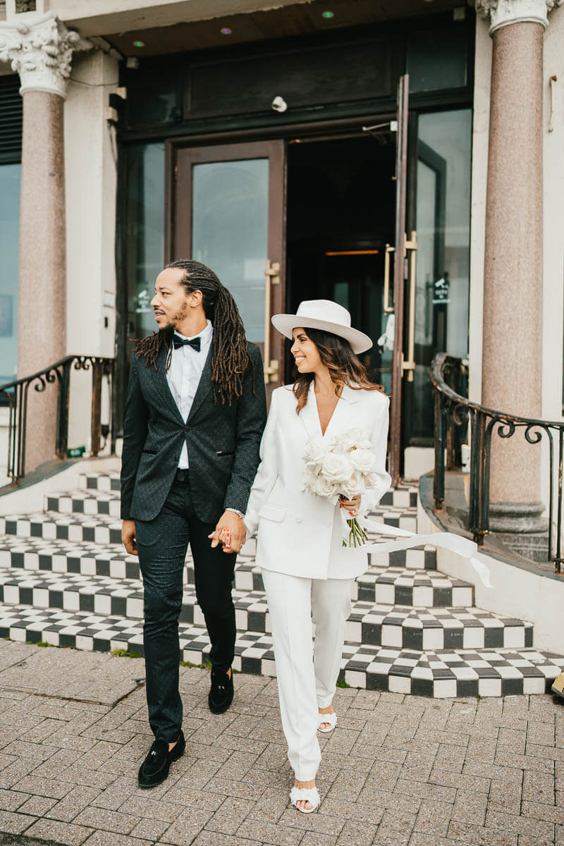 bride and groom walking down lobby steps both looking to the right