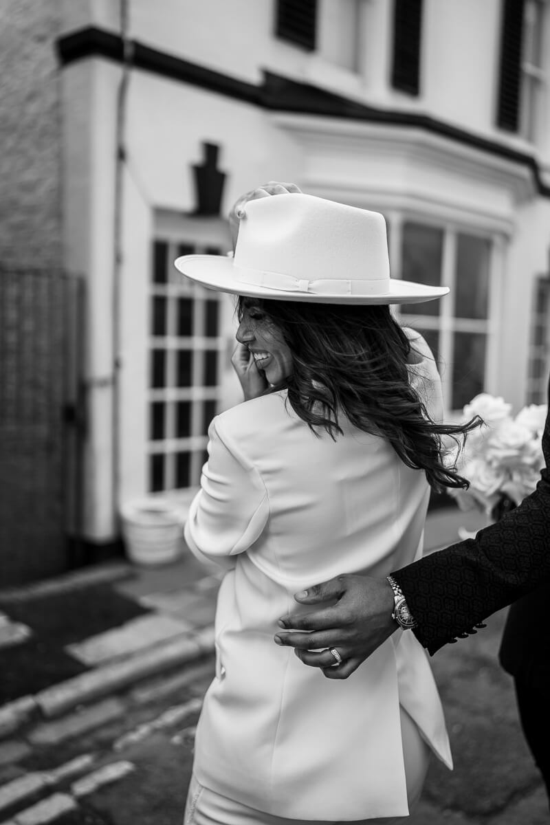bride turning around holding onto her hat groom's hand round her waist