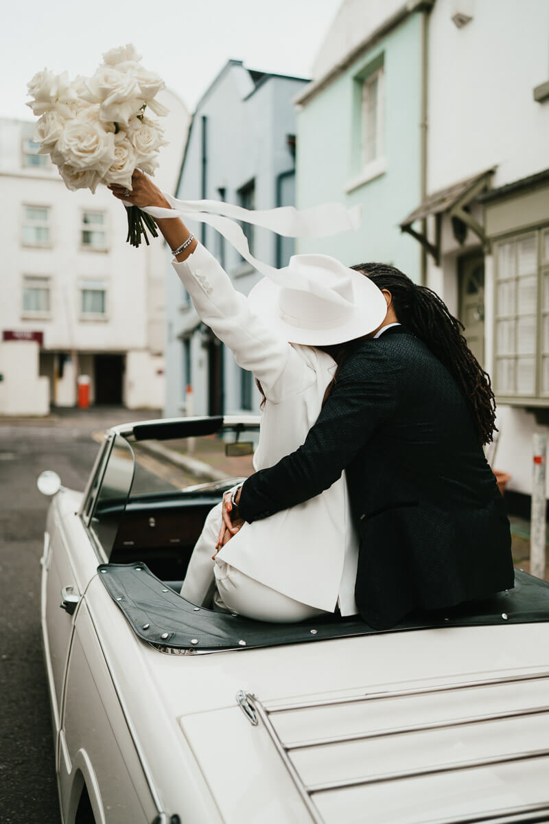 shot of couple from sitting on back of car holding up flowers
