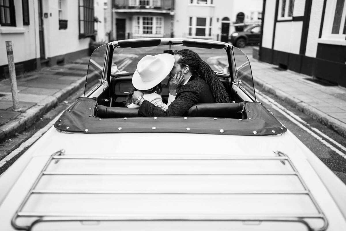 shot of couple sitting in front seats of convertible classy car kissing