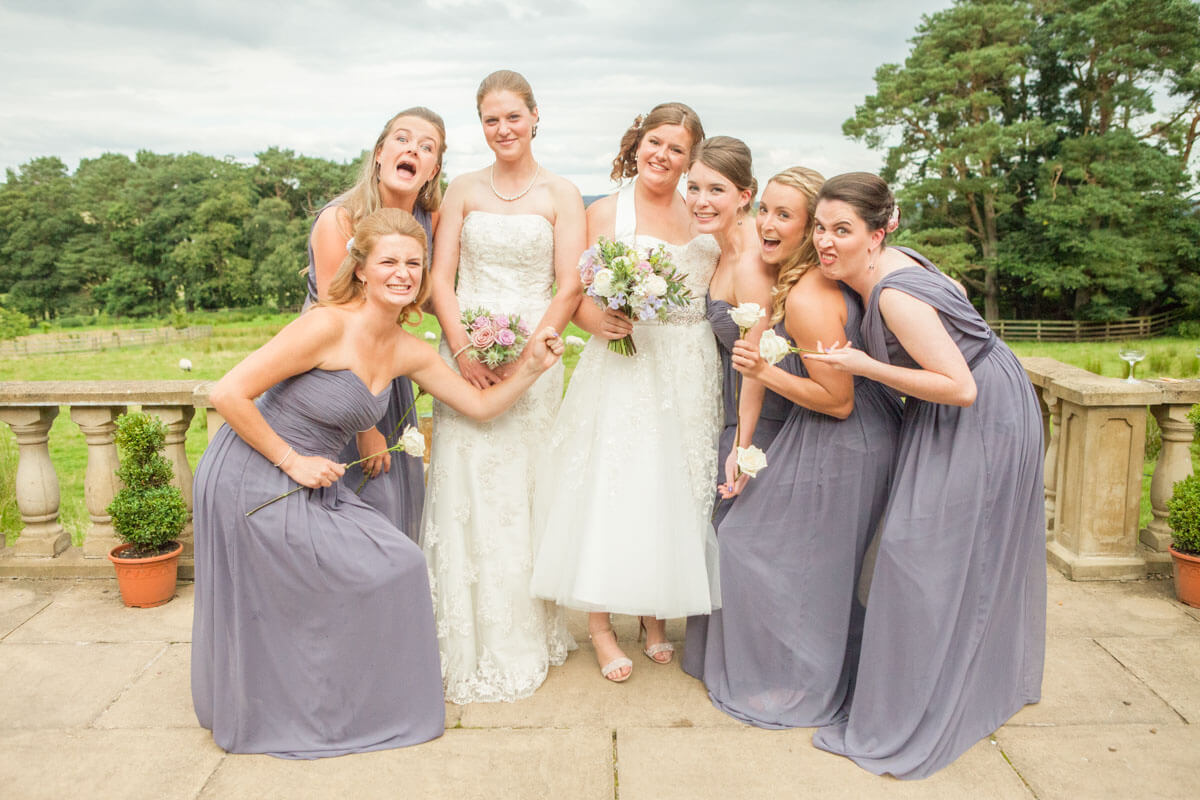 two brides and their bridesmaids pulling faces for their group photo 