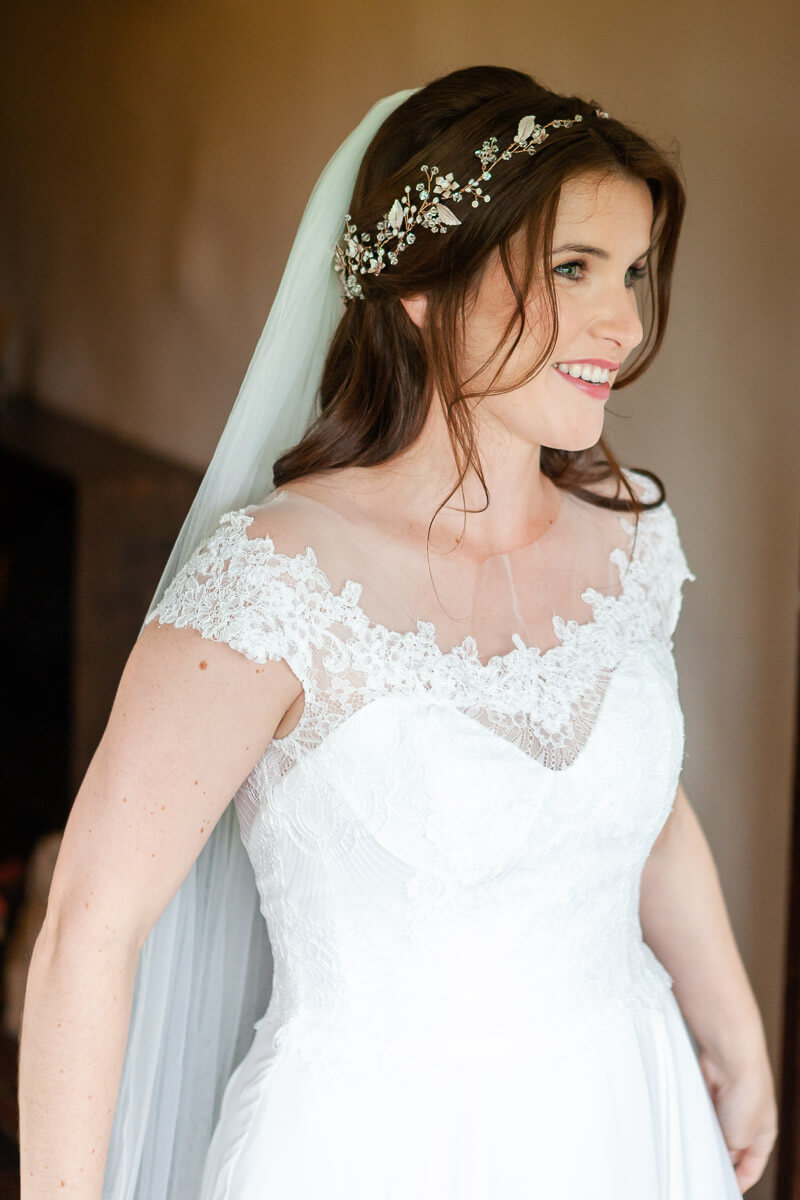 colour image of bride smiling looking away from the camera with hands besides her sides