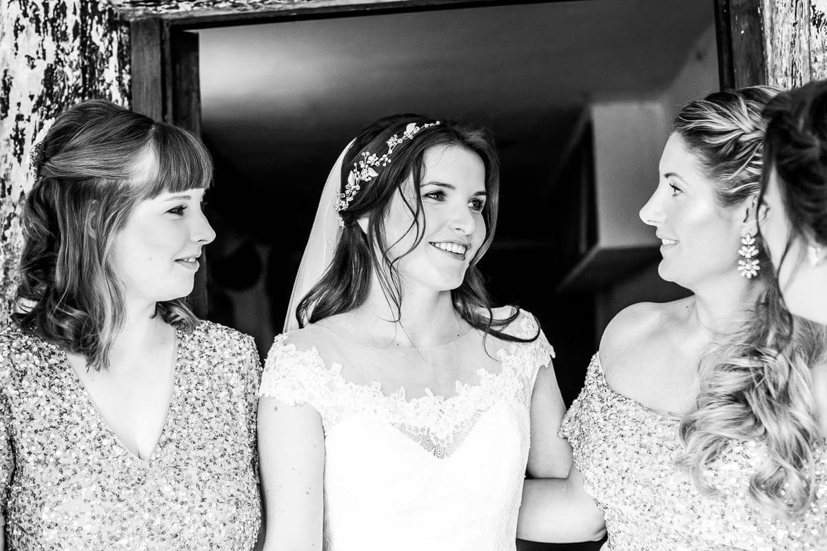 bride looking away from camera smiling with bridesmaids either side