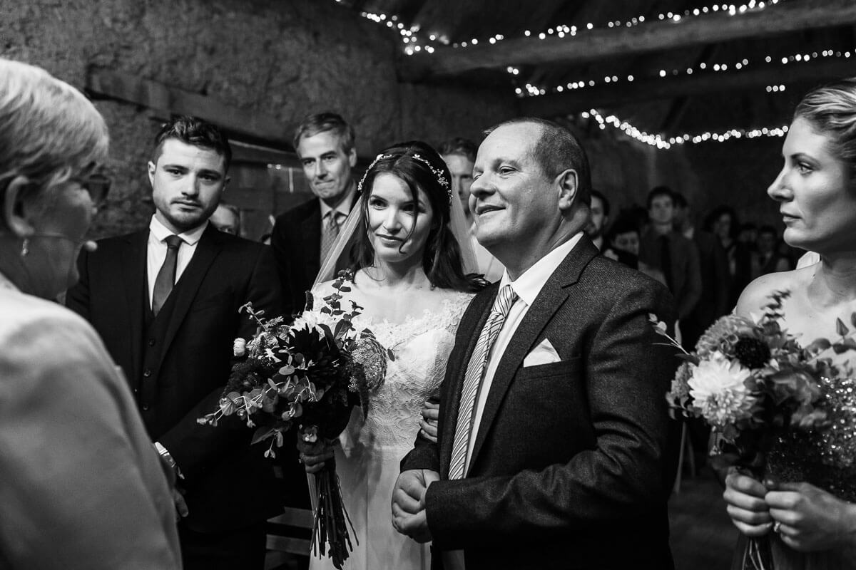 bride standing at front of ceremony room with her father they are holding hands