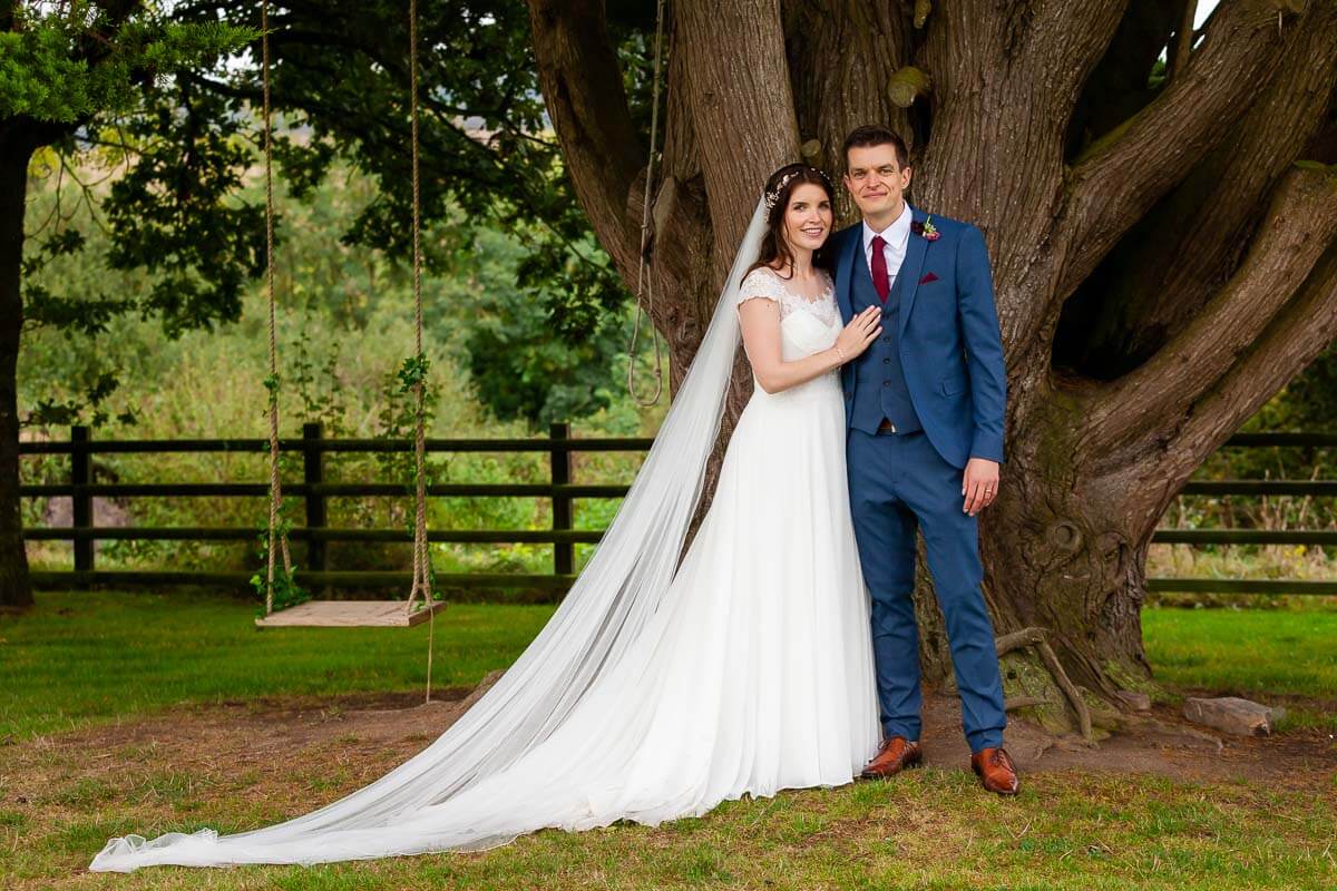 wide angle shot of bride and groom with veil and train laid out bride with her hand on groom's chest