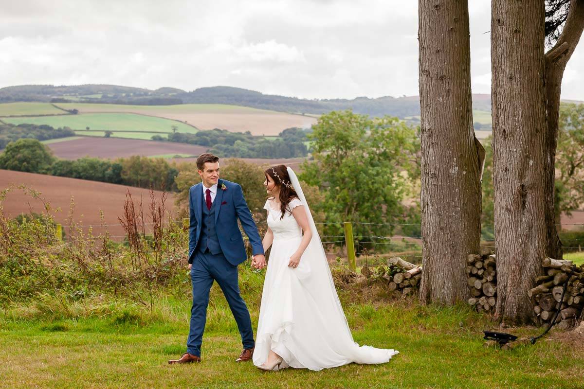 bride and groom walking hand in hand walking along grass lawn
