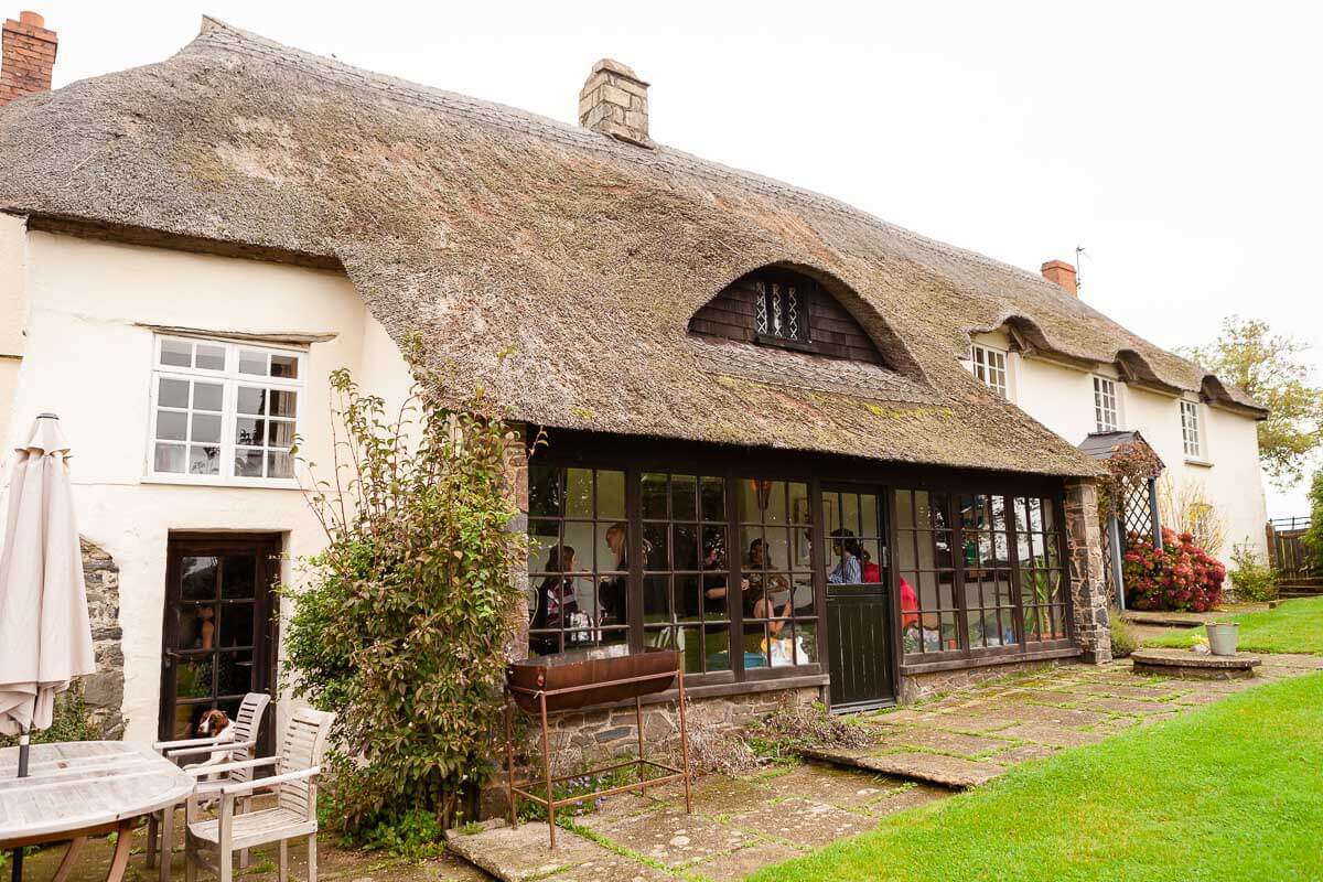 wide angle view of thatched cottage with grass lawn infront