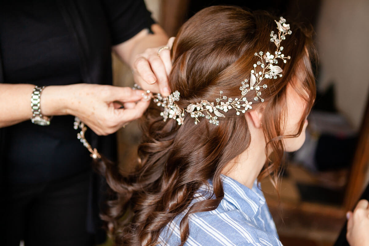 close up of the back of the bride's hair with hairdresser adding in the headdress