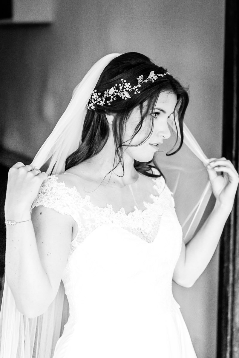 Bride holding her veil out in both hands looking away from the camera