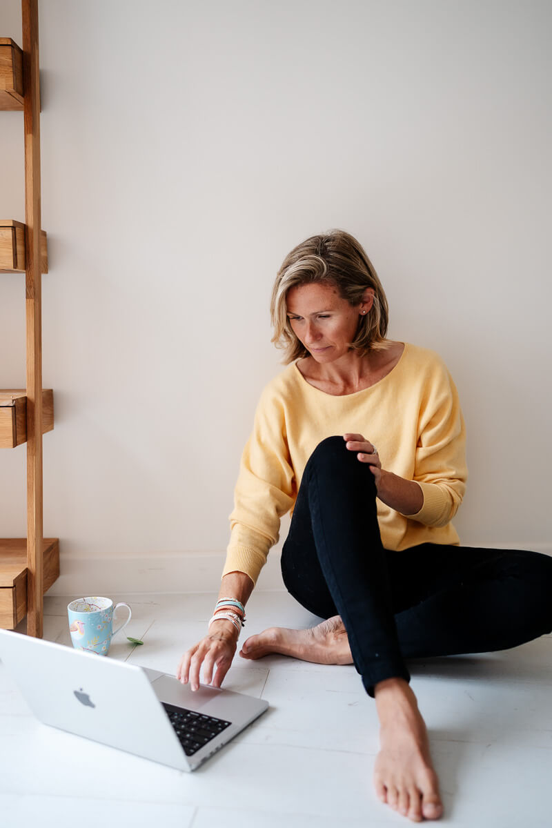 photographer sitting on floor with laptop at feet