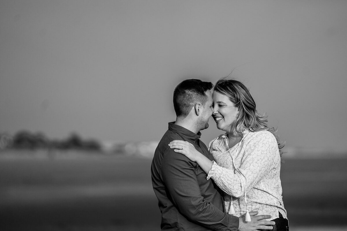 woman places arm on partners shoulder faces close together