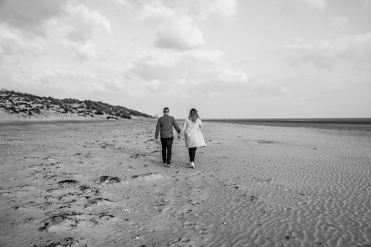 couple walking away from the camera on huge expansive beach