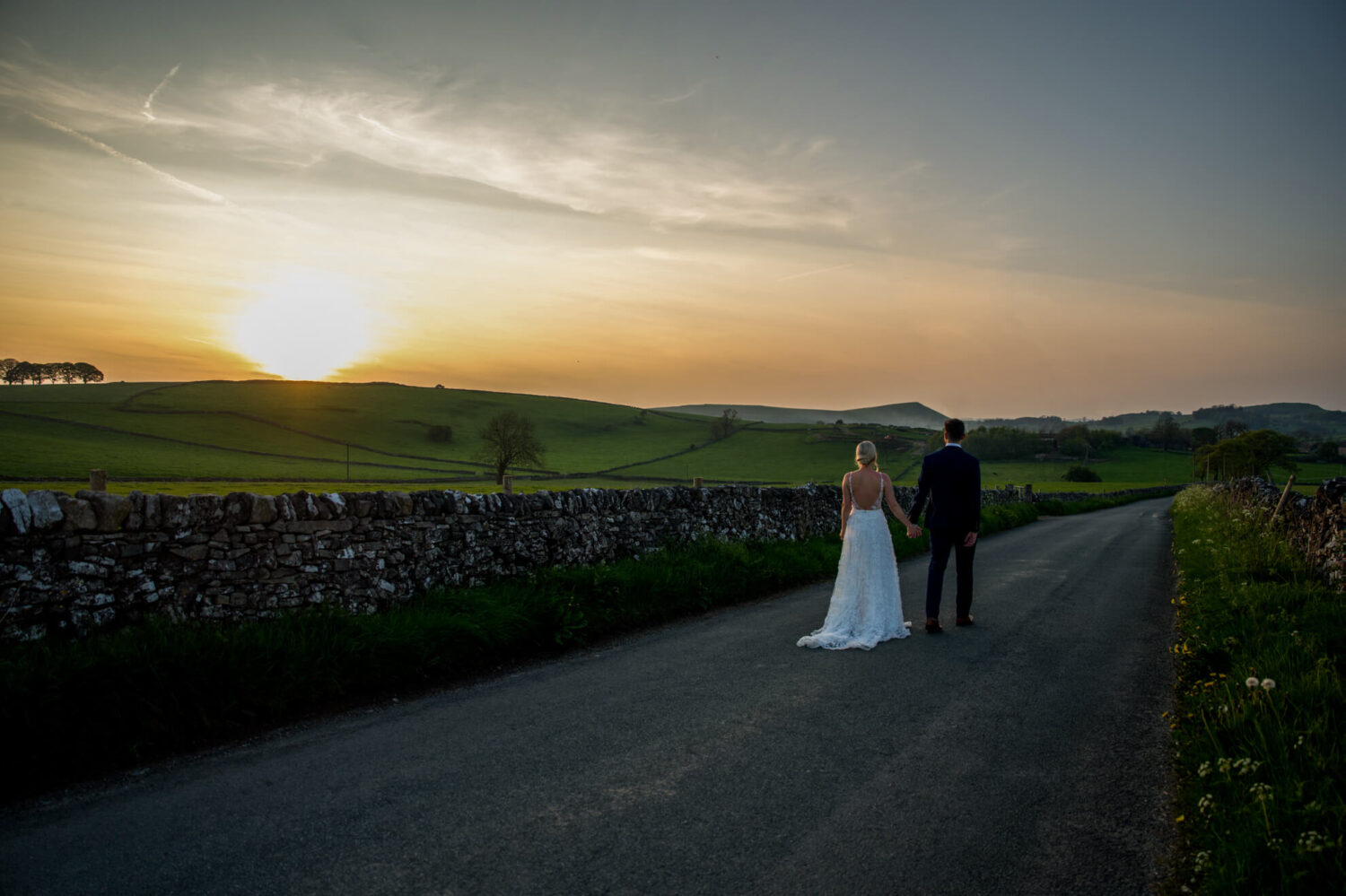 couple walking down country lane at sunset