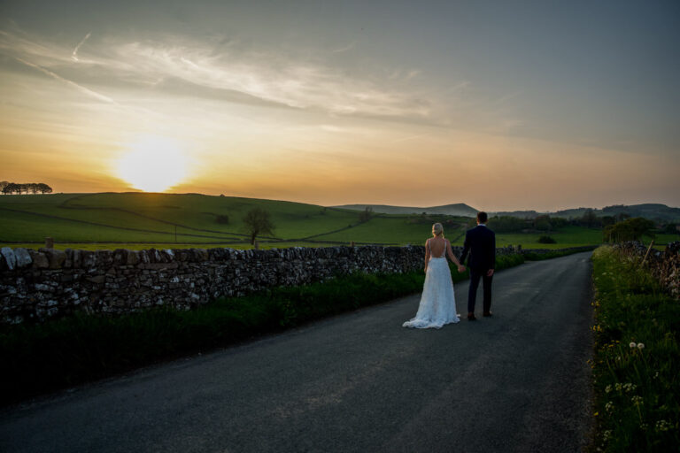 couple walking down country lane at sunset